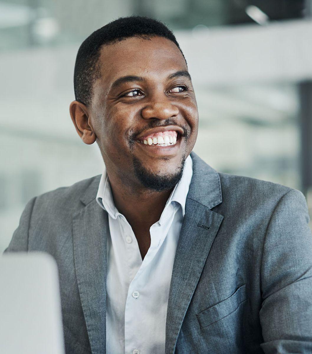 Man wearing gray suit and white shirt smiling and looking off camera.