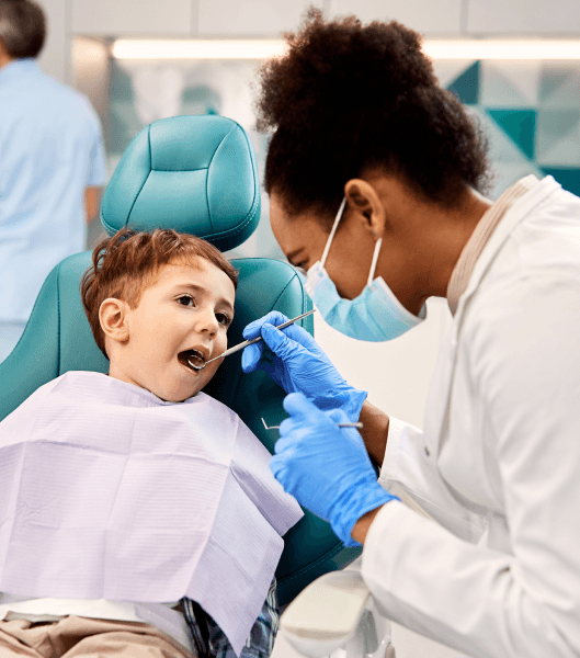 Child in a dentist chair with a dental technician working on his teeth.