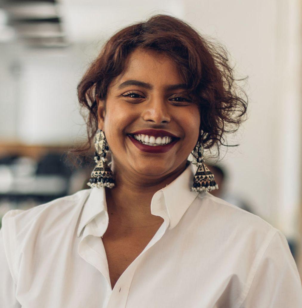 Women wearing white shirt with collar smiling and looking into the camera.