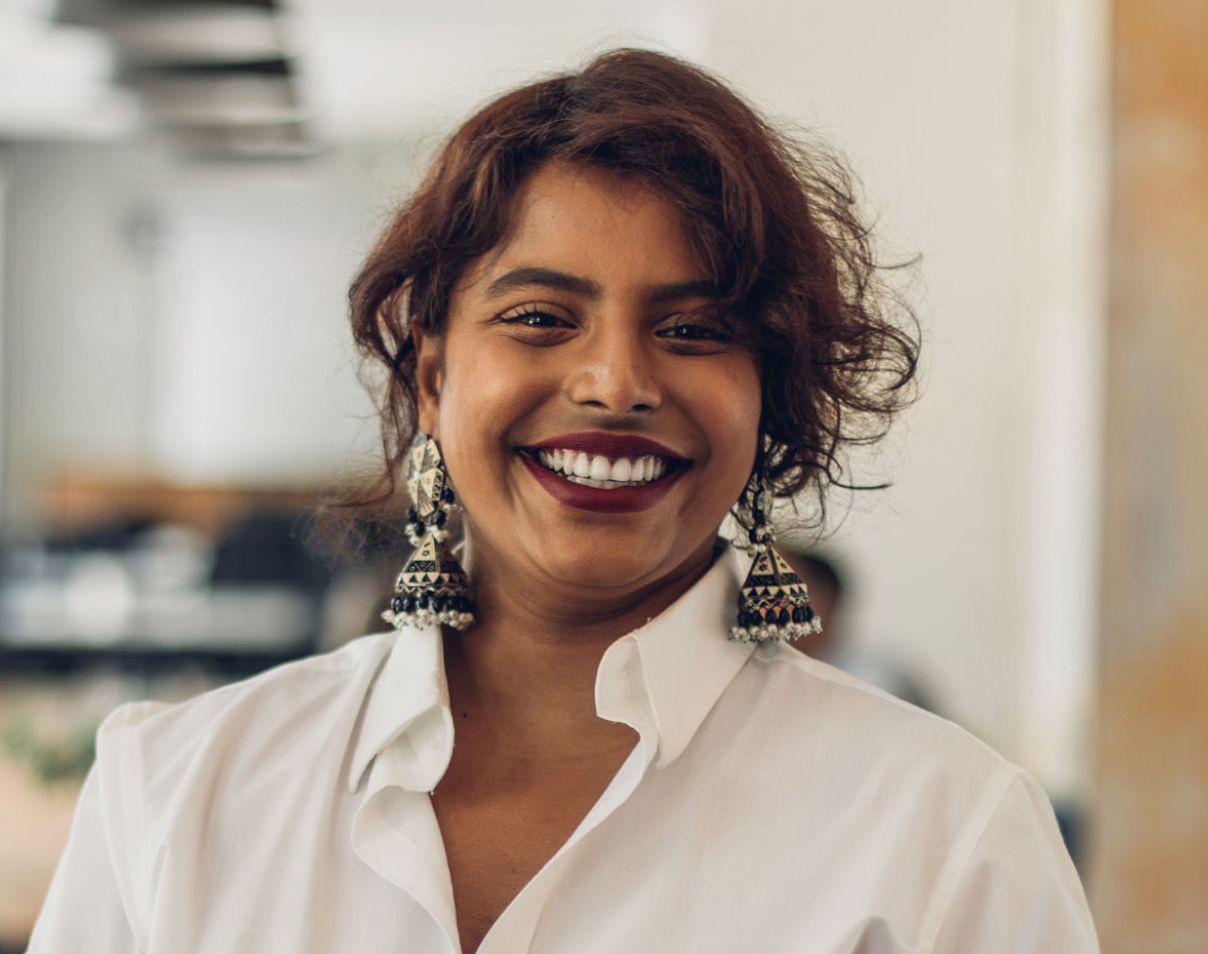 Women wearing white shirt with collar smiling and looking into the camera.