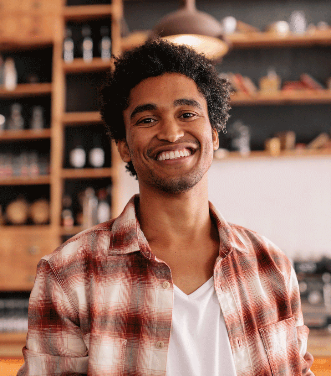 Man wearing flannel and v-neck white shirt smiling and looking directly into the camera.